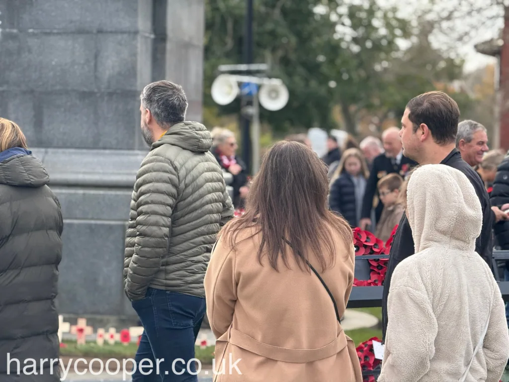 People gather near the cenotaph, with some looking reflective and solemn during the Remembrance Day ceremony.