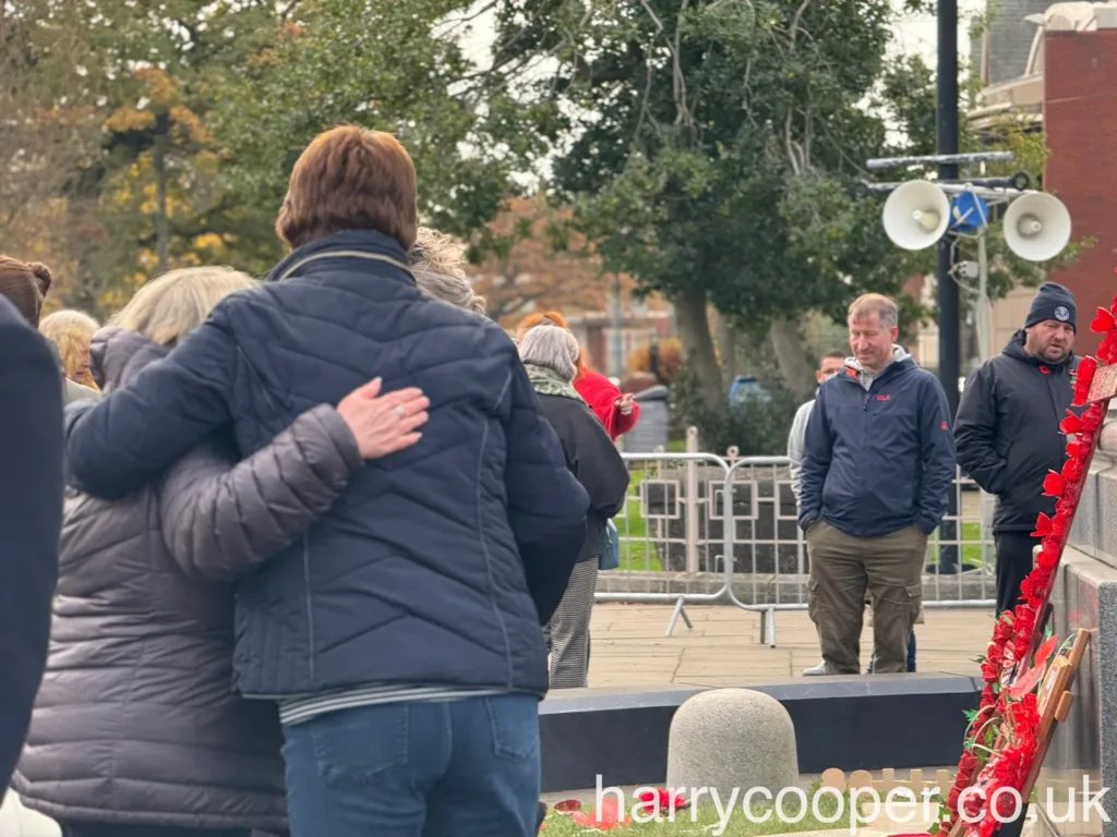 Two people embrace near the cenotaph, showing mutual support as they reflect on Remembrance Day.